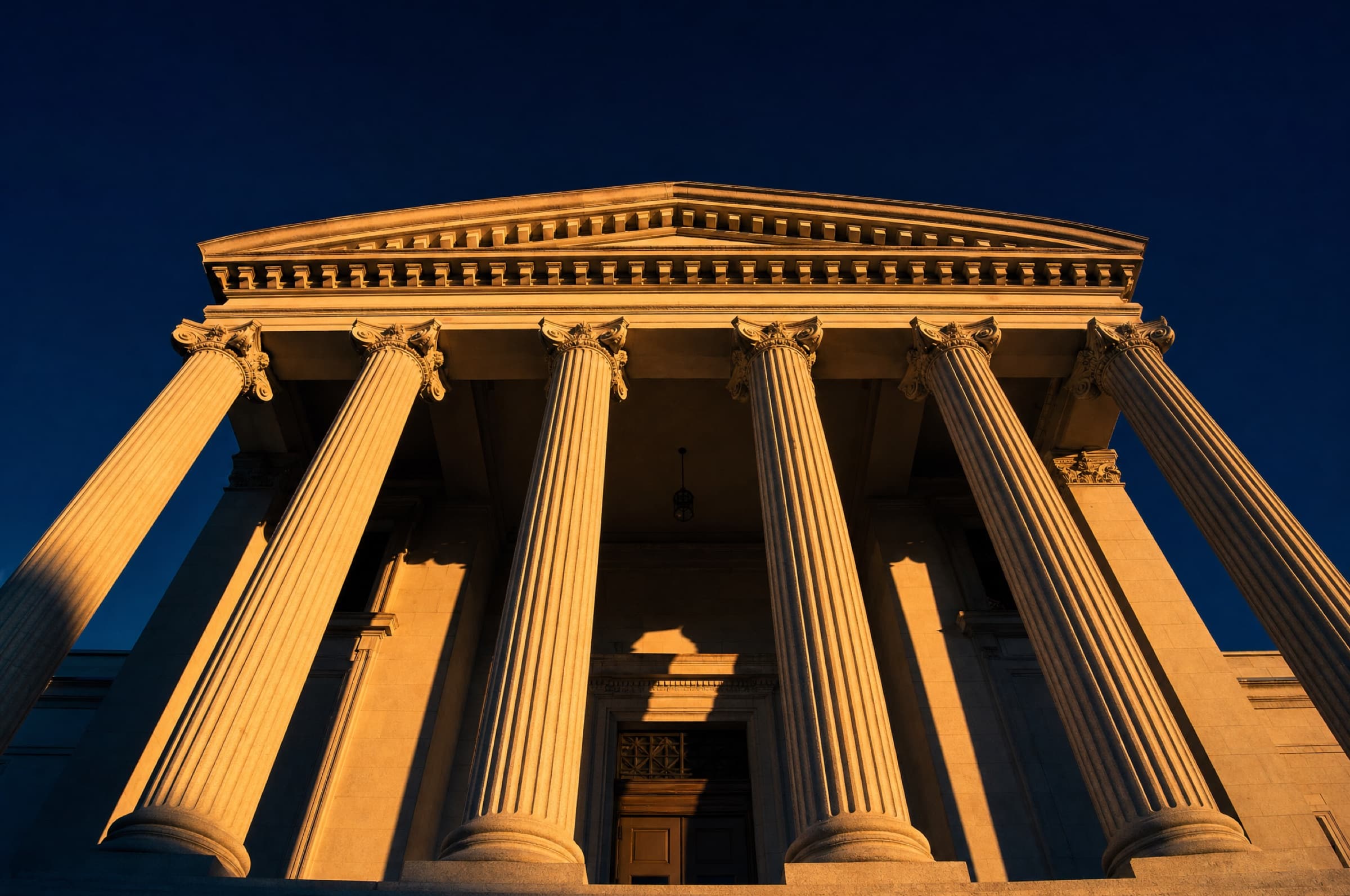 Stone courthouse columns lit by late-afternoon sun